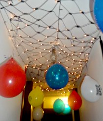 birthday balloons and star wars ballons hanging from our ceiling in a white lights net of 'stars'