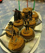 Chocolate cupcakes with darth vader yoda and other star wars figures with lightsaber cake toppers in green blue and red